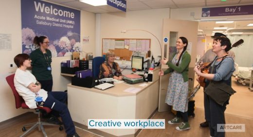 performers with albatross puppet and instruments interact with staff on ward reception