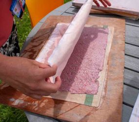laying another cloth over the top of the wet paper sheet