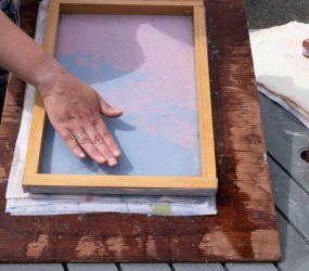 squeezing out the excess water from the deckle