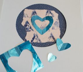 cut out blue foil hears on blue monoprint