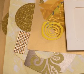 pile of paper, gold card, and yellow shapes