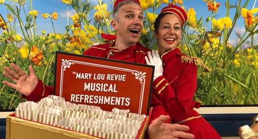 Performers dressed in red as ushers with tray of 'musical refreshments'