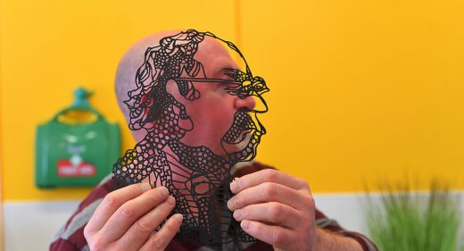 Man holds up outline black and transparent image of himself alongside his own side profile