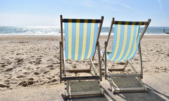 photograph of two blue and yellow deckchairs on the beach