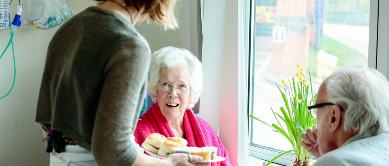 Serving scones to patients at table on ward