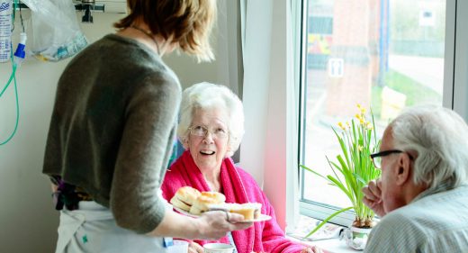 Serving scones to patients at table on ward
