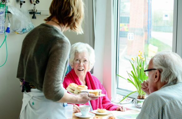 Serving scones to patients at table on ward