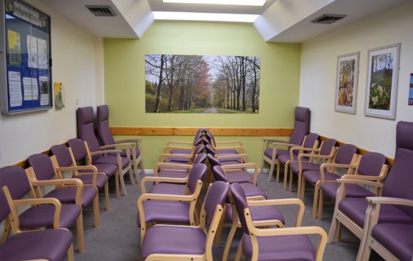 Large scale artwork of avenue of trees at end of waiting area, with lilac seating in front