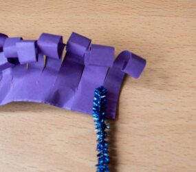 laying the pipe cleaner on one end of the curled card