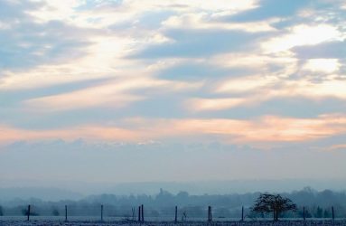 photo of early morning soft glowing light above misty and frosty ploughed field in winter